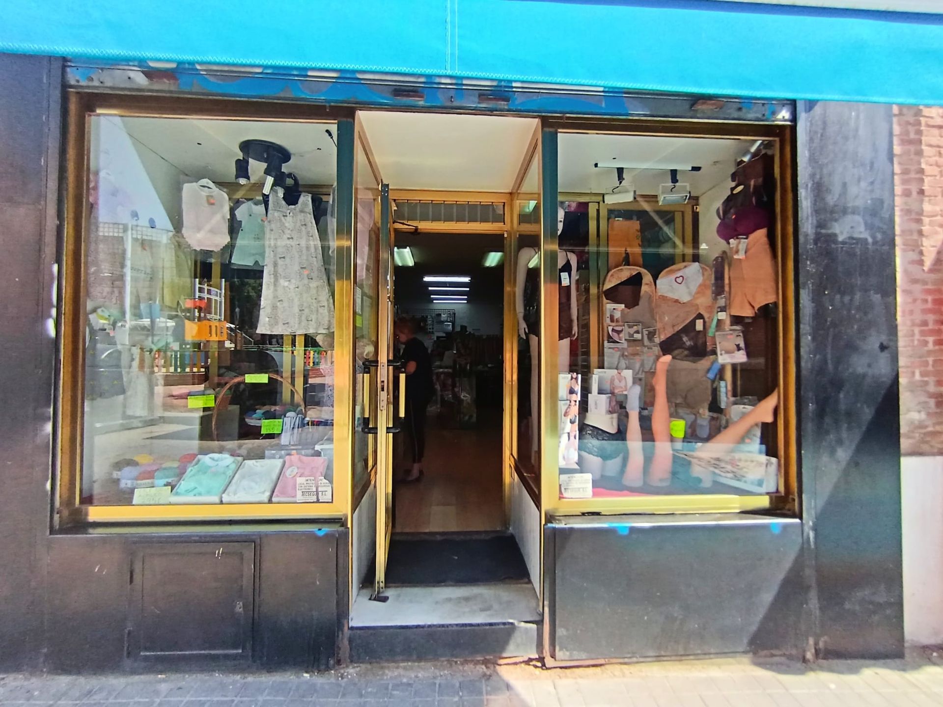 Una tienda con un toldo azul y ropa en exhibición.