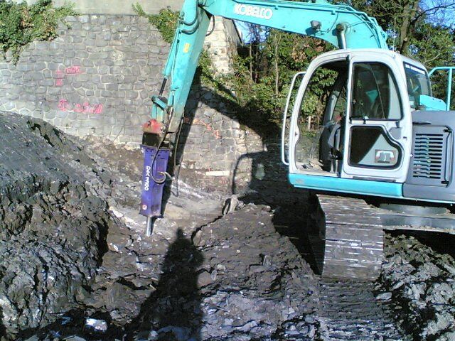 Tractopelle perçant le sol dans une tranchée lors d'un travail de terrassement
