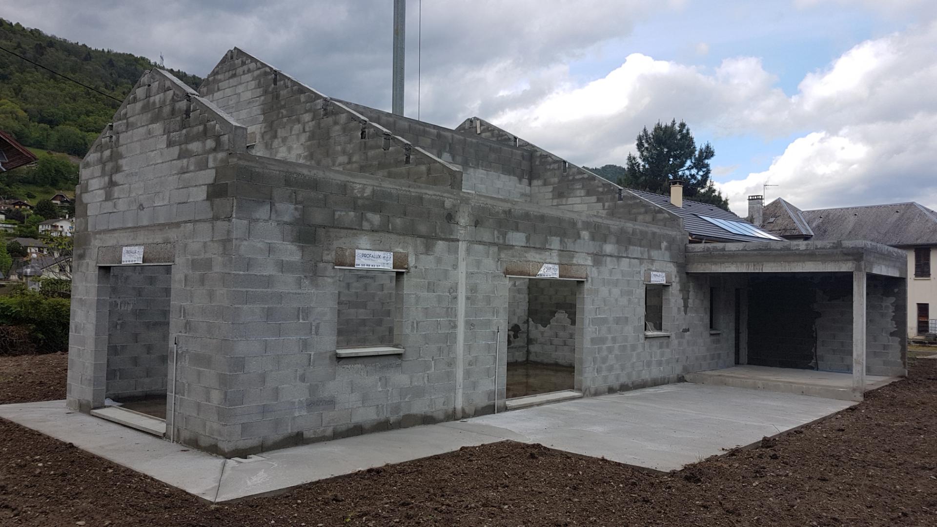 Construction d'une maison avec travaux de terrassement, revêtement en béton, élévation des murs, sans toit ni peinture