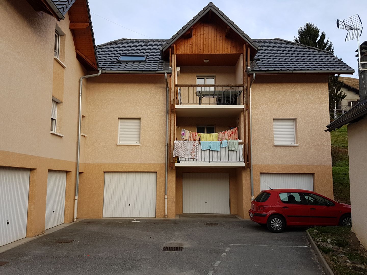 Logement collectif jaune et orange pale avec balcon au premier et deuxième étage, et des garages au rez-de-chaussée