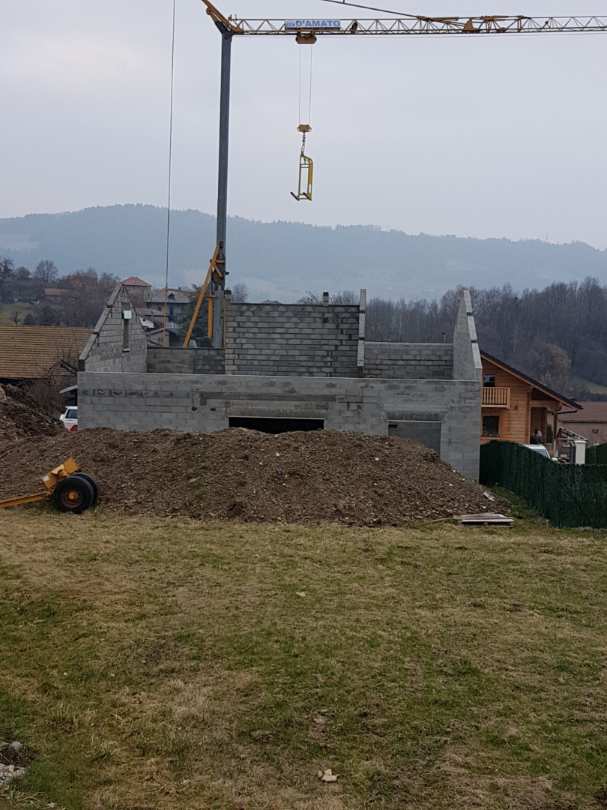Vue de loin d'un chantier de construction d'une maison pour l'instant sans toit avec un terrassement visible au premier plan