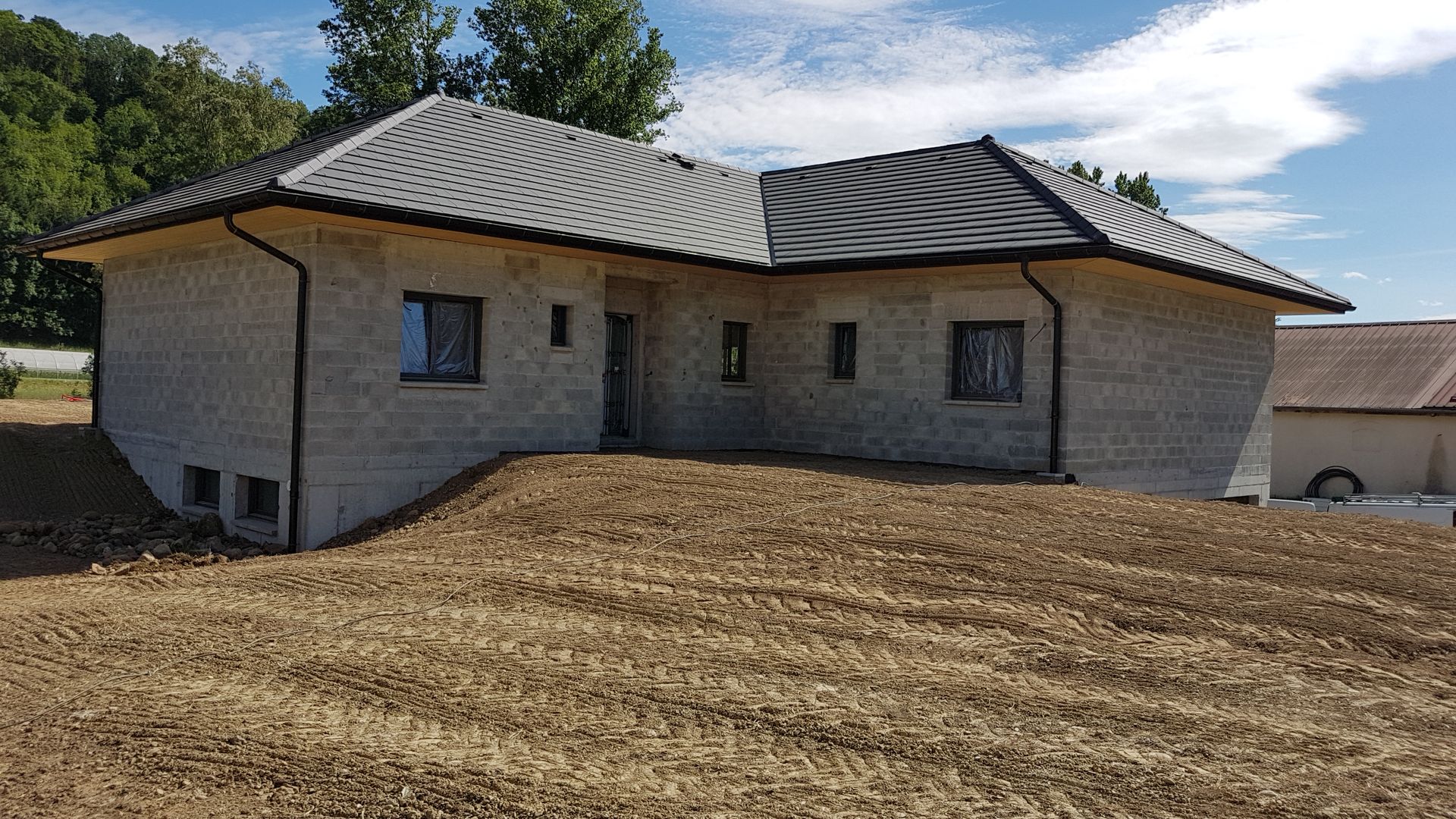 Maison individuelle avec terrassement de l'espace devant, déjà construite mais sans peinture