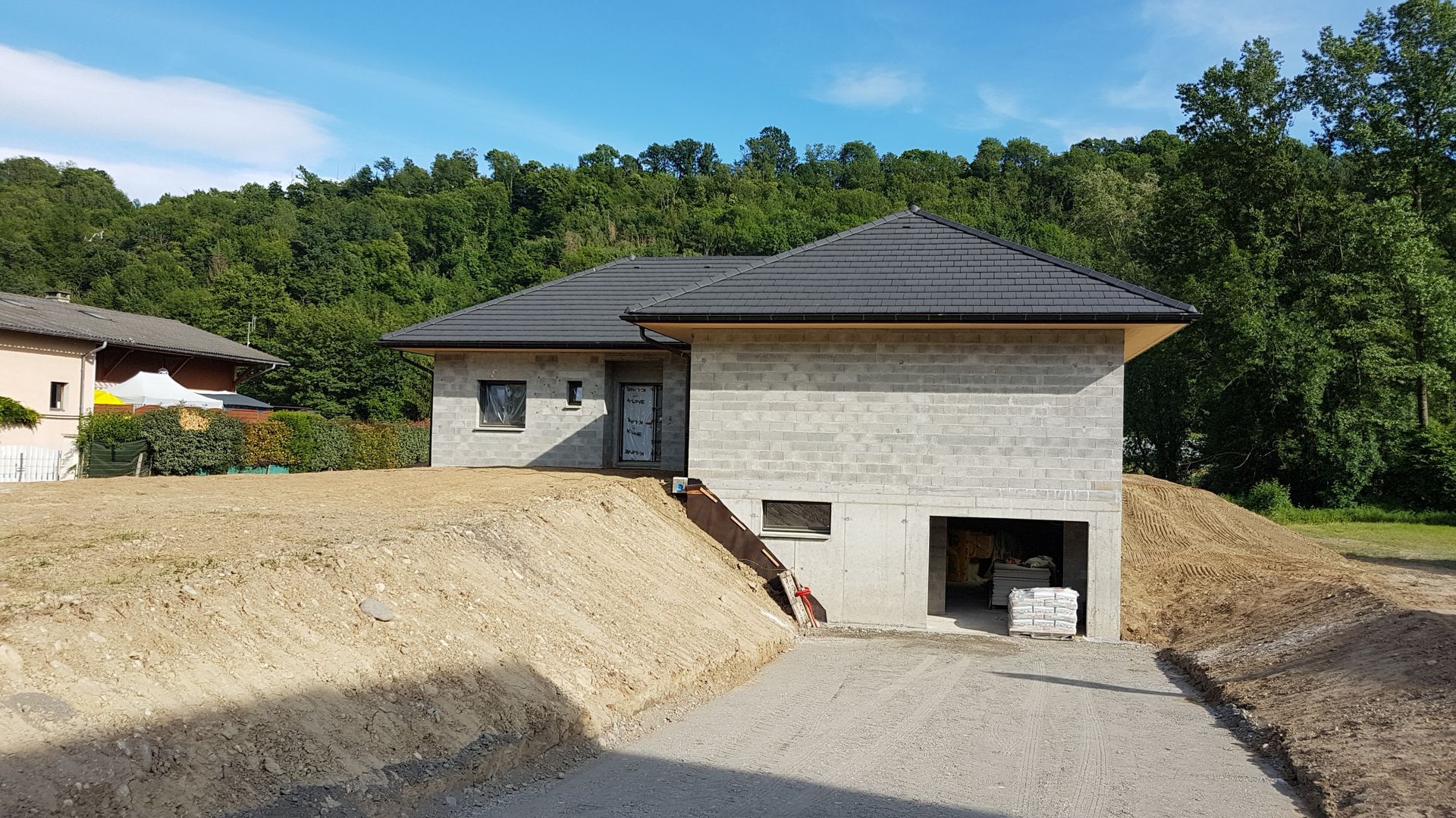 Voirie neuve conduisant à une maison en cours de construction dont les murs ne sont pas peints