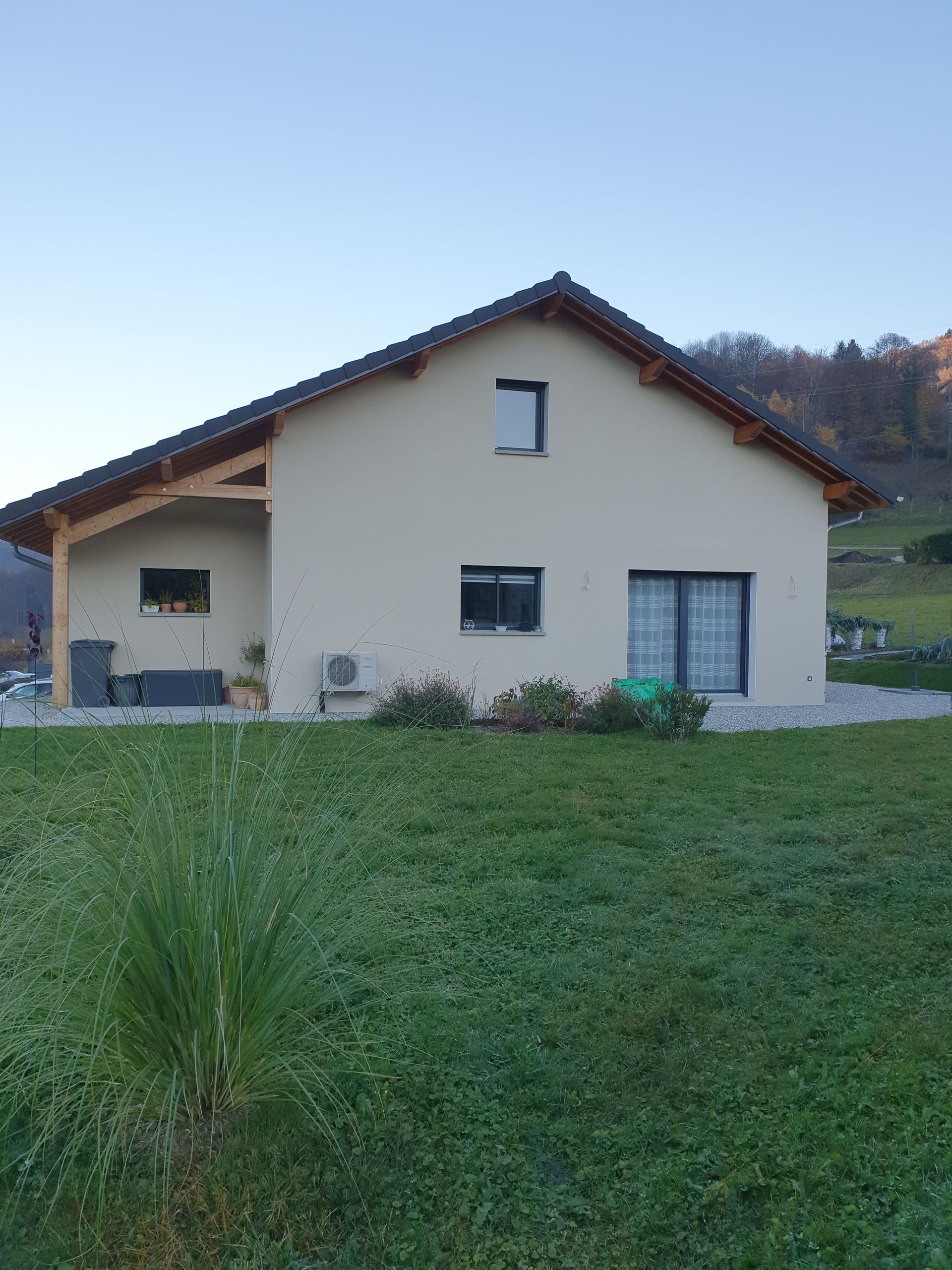 Vue de côté d'une maison individuelle dont la construction est terminée, avec espace vert au premier plan