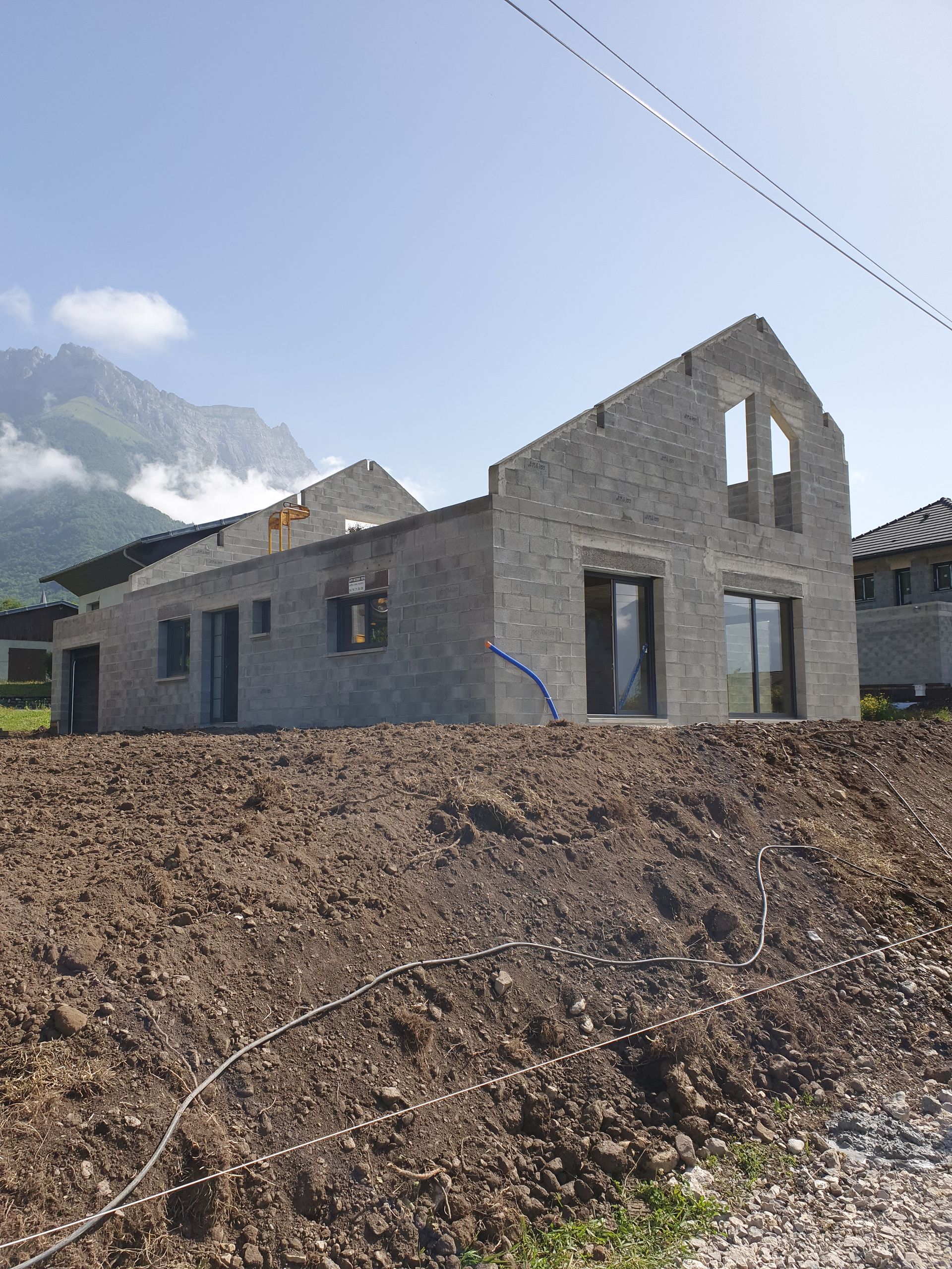 Vue d'ensemble d'une bâtisse en béton en cours de construction avec le terrain terrassé au premier plan