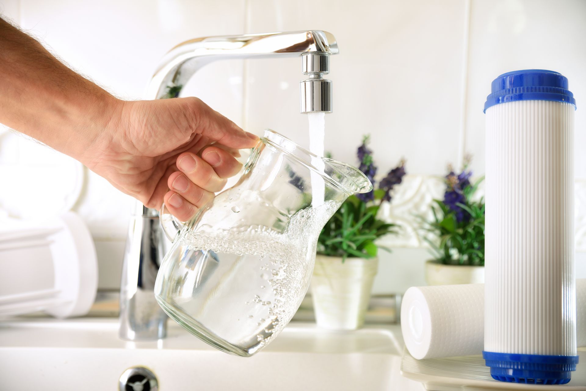 Une personne remplit une carafe d'eau du robinet filtrée