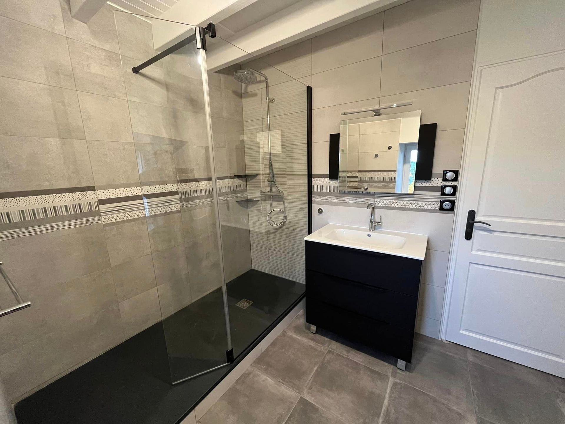 Salle de bains avec meuble noir et douche à l'italienne