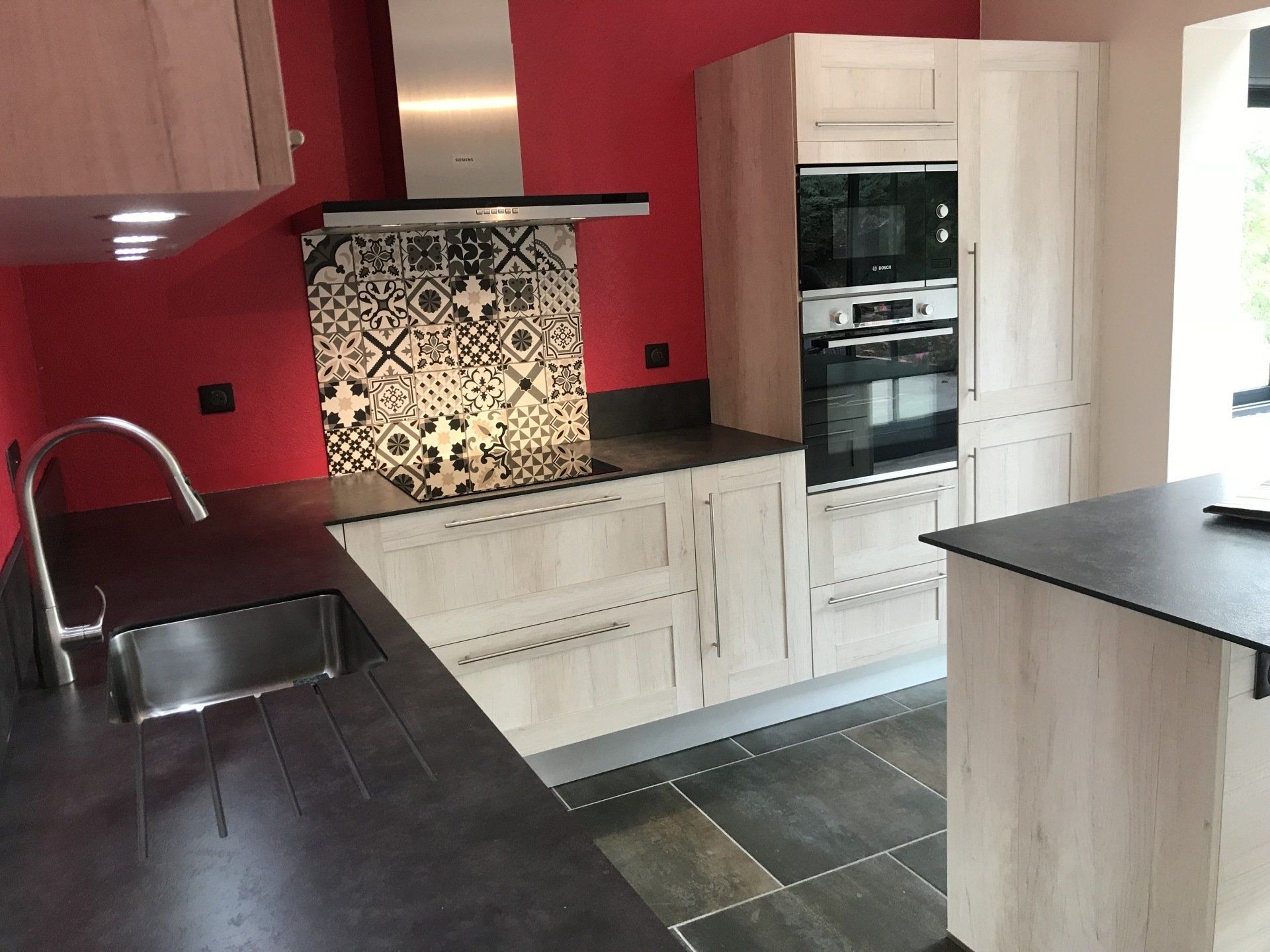 Cuisine rénovée de couleur rouge et avec un pan en carrelage