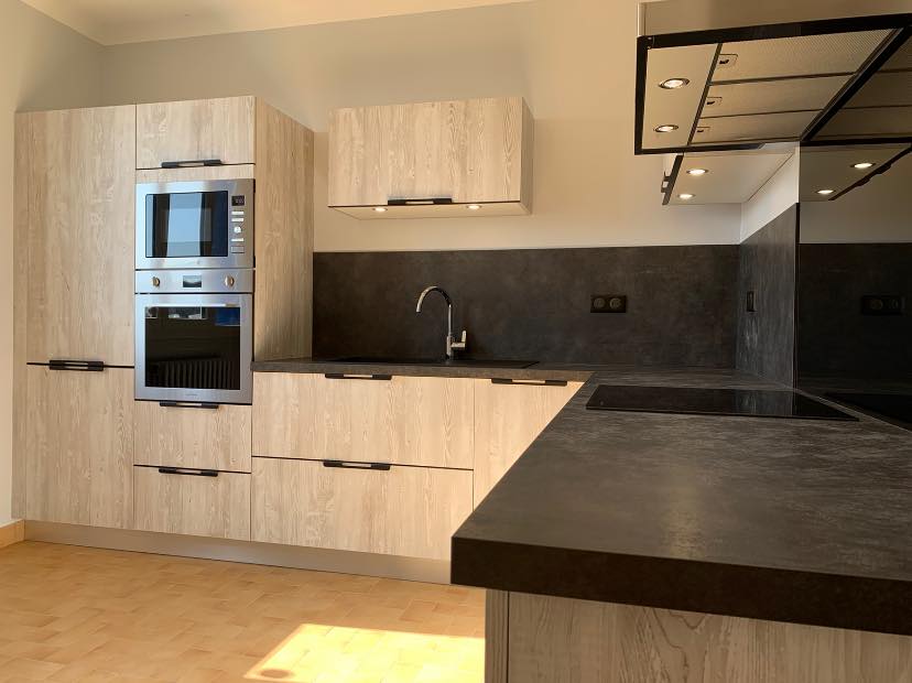 Cuisine équipée avec meubles en bois clair : four et plan de travail