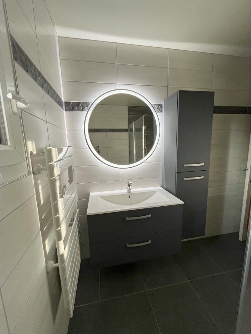 Lavabo et glace ronde dans une salle de bains aux meubles gris
