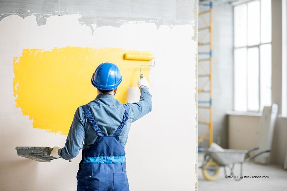 Mann streicht eine Wand gelb