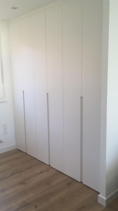 Armario empotrado blanco de seis puertas en habitación con suelo imitación madera.