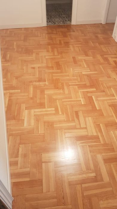 Suelo de parquet de madera en forma de espiga de color marrón claro.