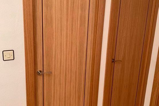 Puertas de armario de madera y un interruptor de luz en una pared blanca.