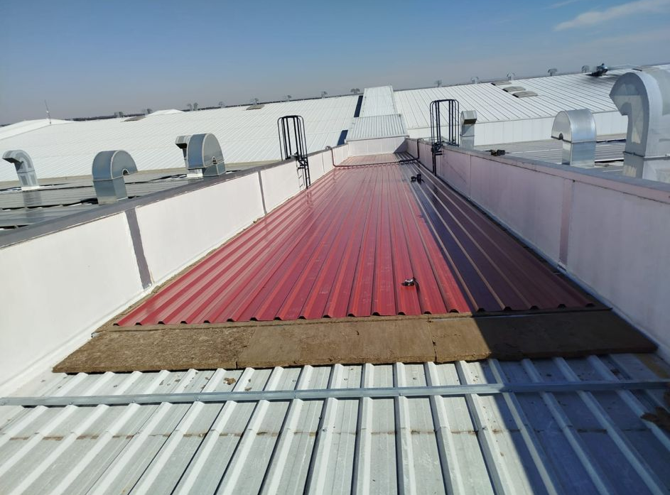 Pasarela roja en una azotea con unidades de climatización blancas bajo un cielo azul despejado.