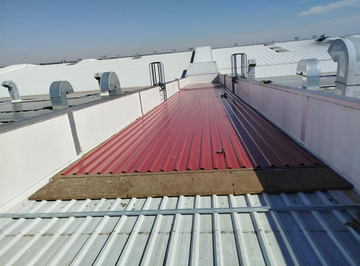 Pasarela roja en una azotea con unidades de climatización blancas bajo un cielo azul despejado.