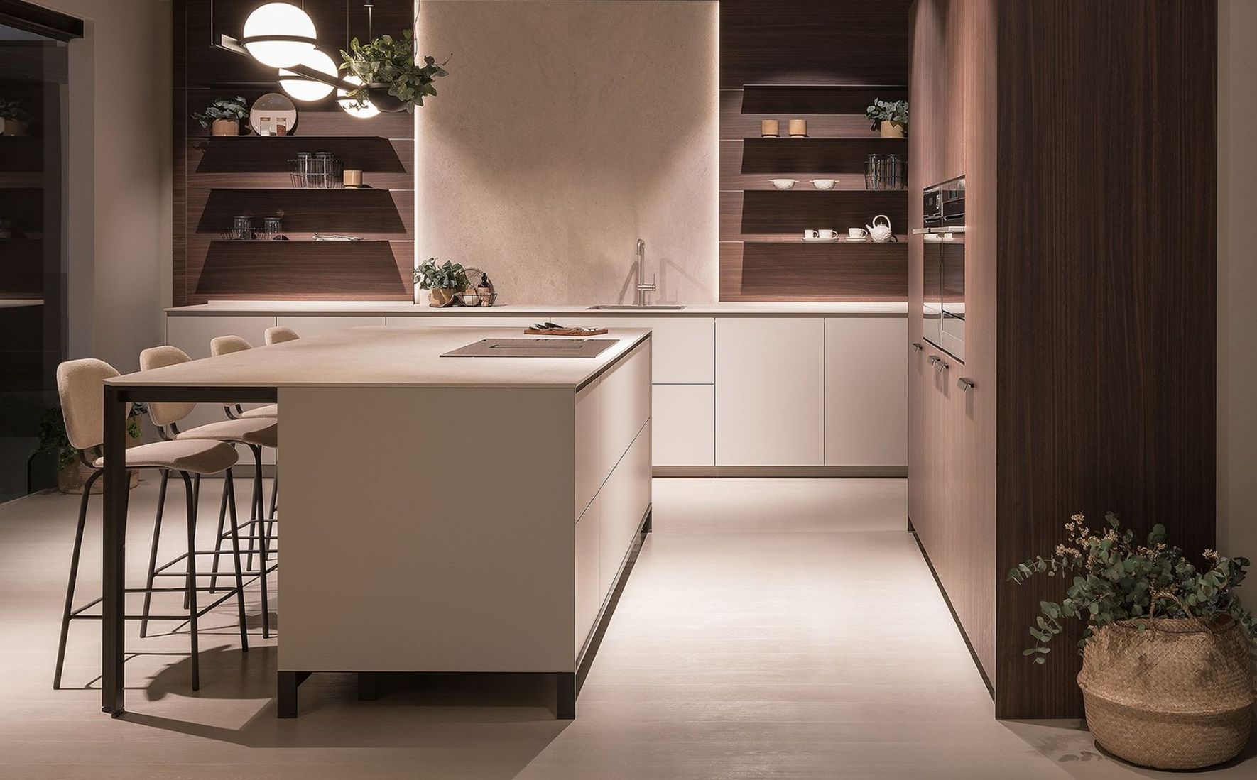 Cocina moderna con isla central, armarios de madera cálida, lámparas colgantes y plantas en macetas.
