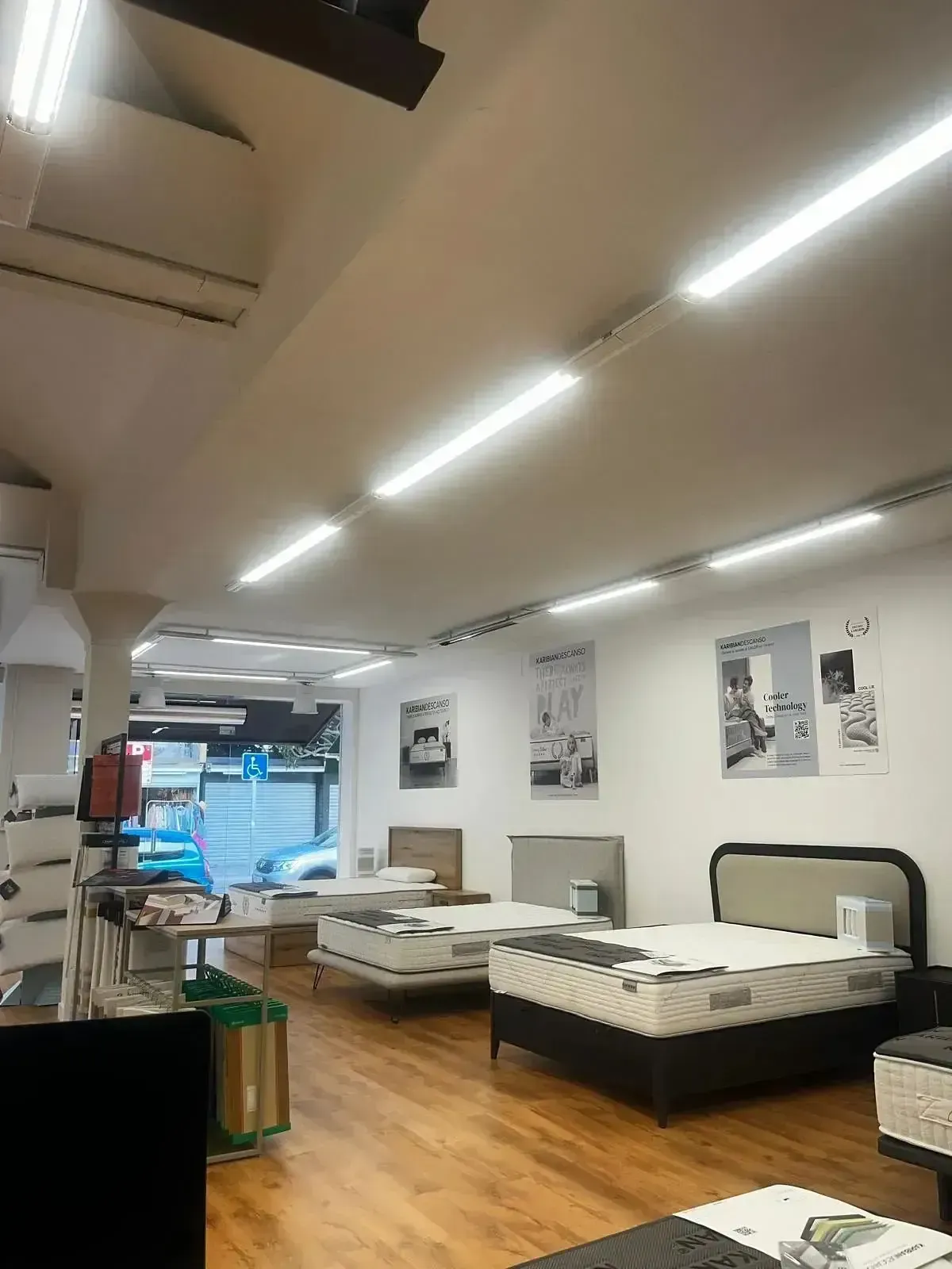 Una luminosa sala de exposición de colchones con varias camas sobre suelo de madera.