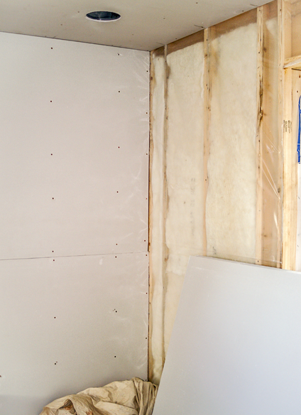 Coin intérieur d'une pièce en construction ; cloisons sèches, isolation et montants en bois sont visibles.