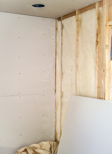 Coin intérieur d'une pièce en construction ; cloisons sèches, isolation et montants en bois sont visibles.