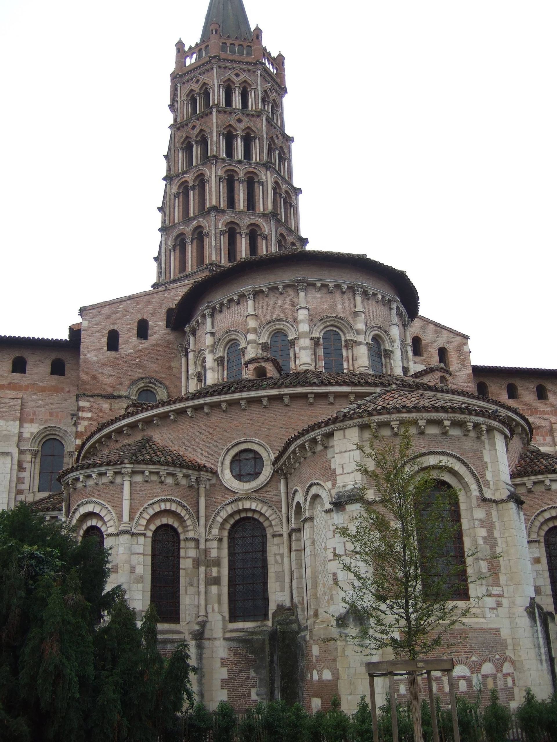 La basilique Saint-Sernin de Toulouse, en France, avec son haut clocher roman à plusieurs niveaux et son abside en pierre.