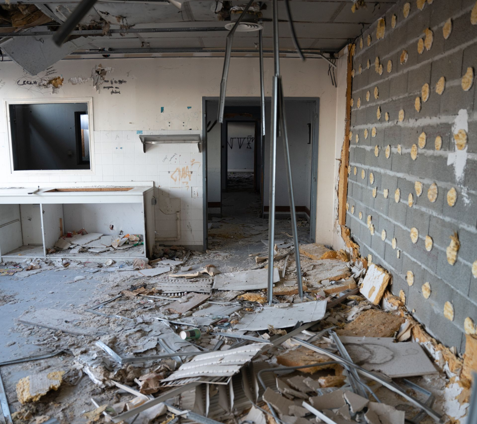 Intérieur d'un bâtiment abandonné avec des débris au sol et des murs endommagés.