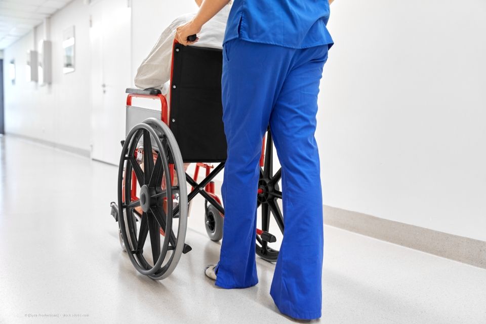 Pflegekraft mit Person im Rollstuhl