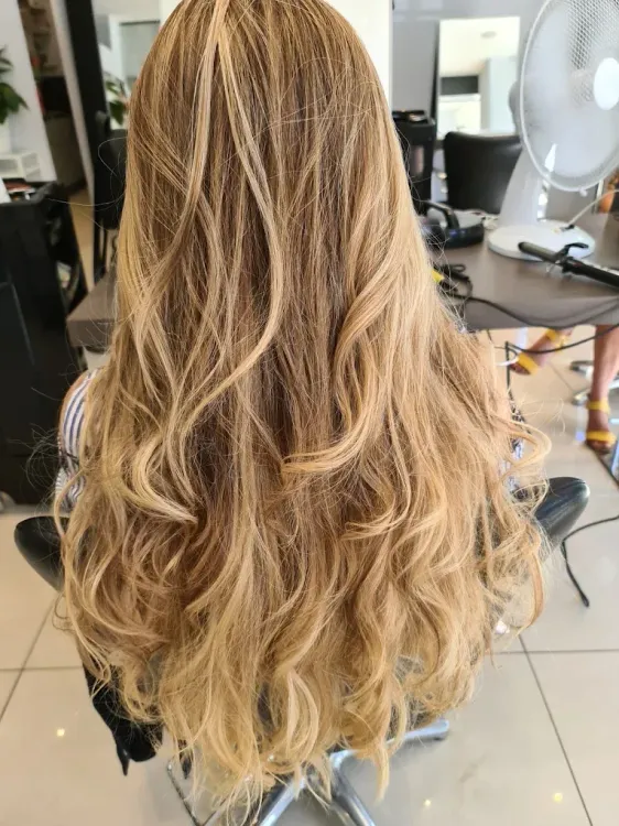 De longs cheveux blonds ondulés, vus de dos, sur un fauteuil de salon.