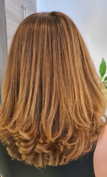 Vue de dos de cheveux châtain clair mi-longs avec des ondulations souples et des reflets subtils
