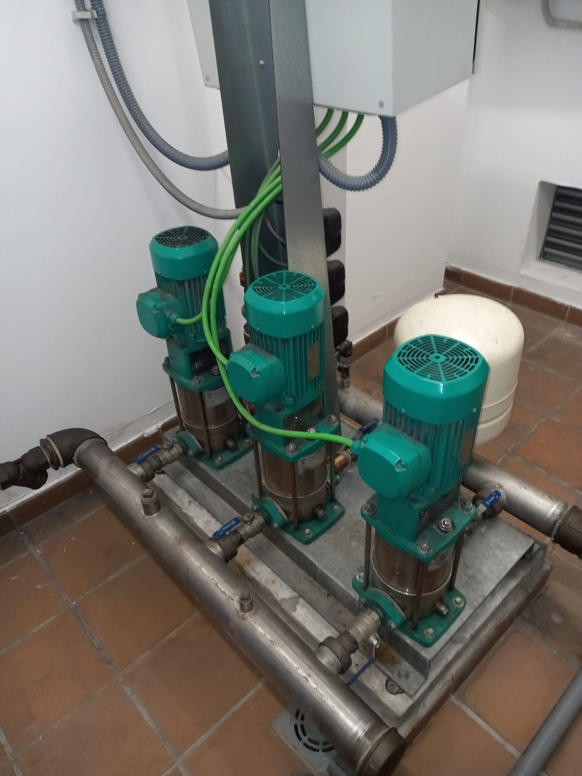 Tres motores verdes están sentados encima de una plataforma de acero inoxidable.