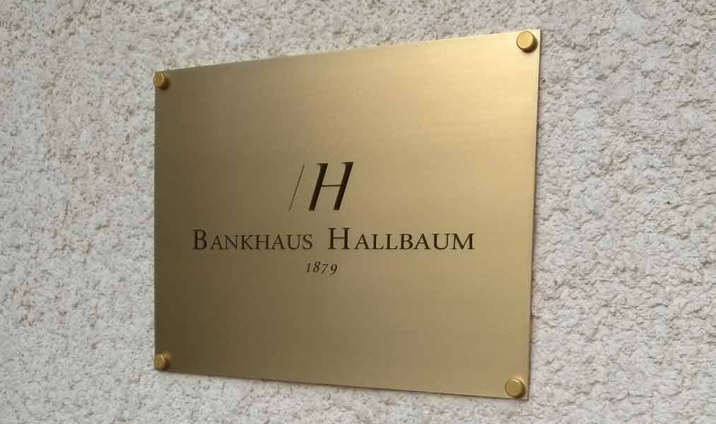 Ein goldenes Schild an einer Wand mit der Aufschrift „Bankhaus Hallbaum“