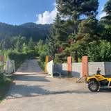 Allée menant aux montagnes et aux arbres, un quad jaune est garé sur la droite.