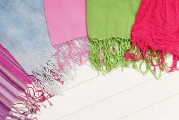 Un grupo de bufandas de colores están colocadas una encima de otra sobre una superficie blanca.