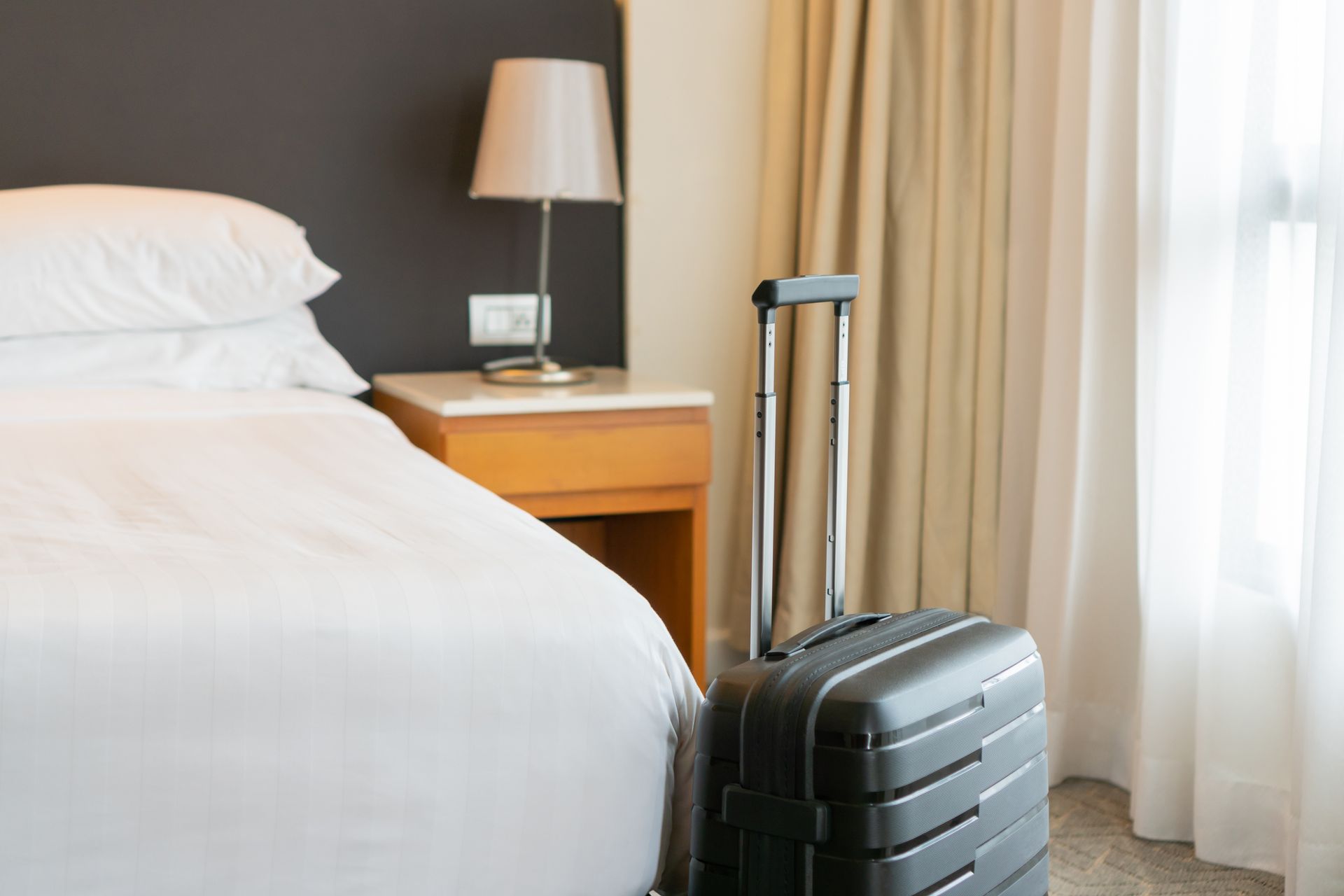 Valise devant le lit d'une chambre d'hôtel