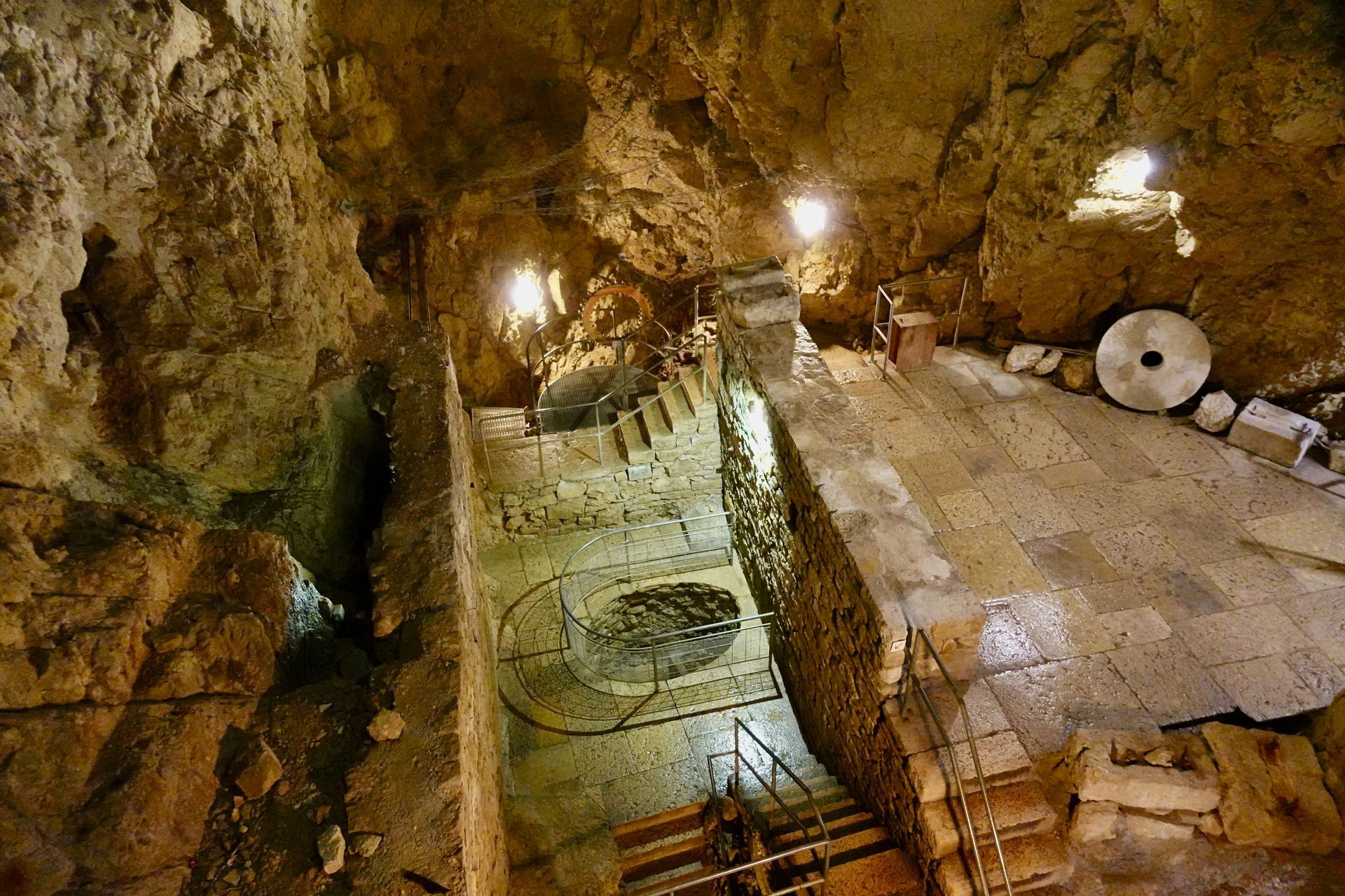 Grotte éclairée avec sol carrelé et escaliers en pierre 