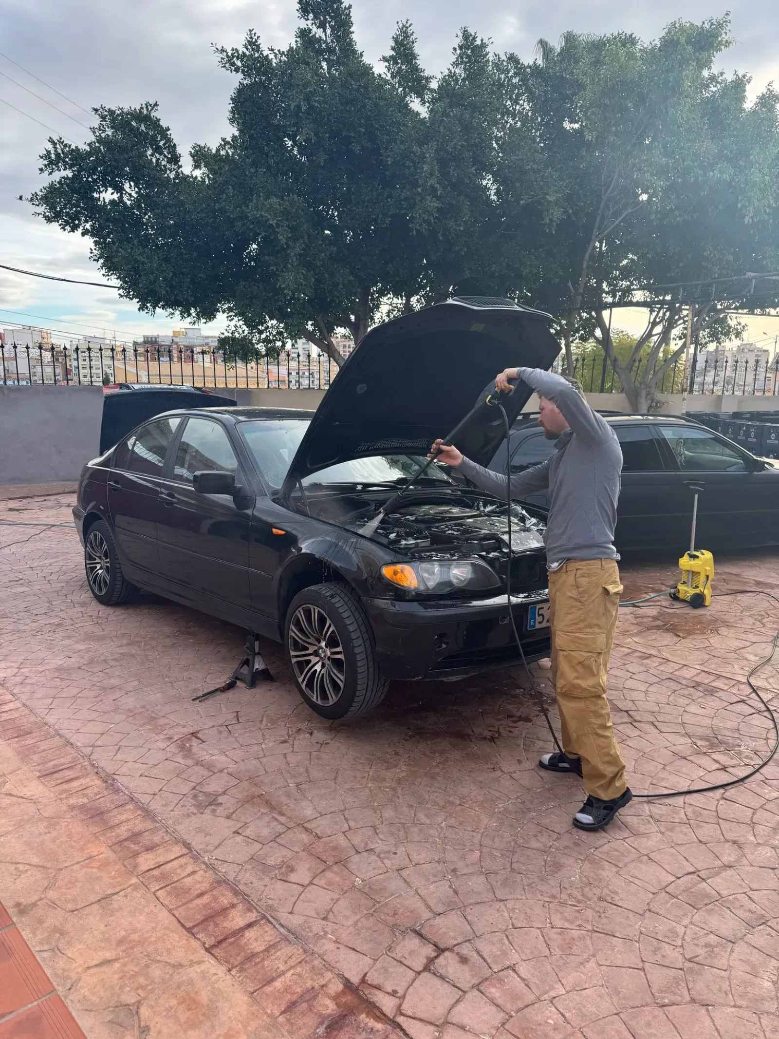 Un hombre está mirando debajo del capó de un coche.