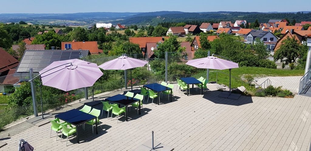Terrasse mit Tischen, Stühlen und Sonnenschirmen.