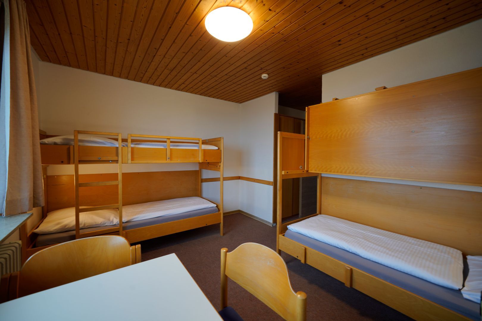 Ein Zimmer mit Etagenbetten und einem Tisch darin