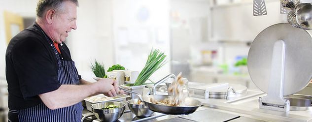 Ein Mann kocht in einer Küche Essen.