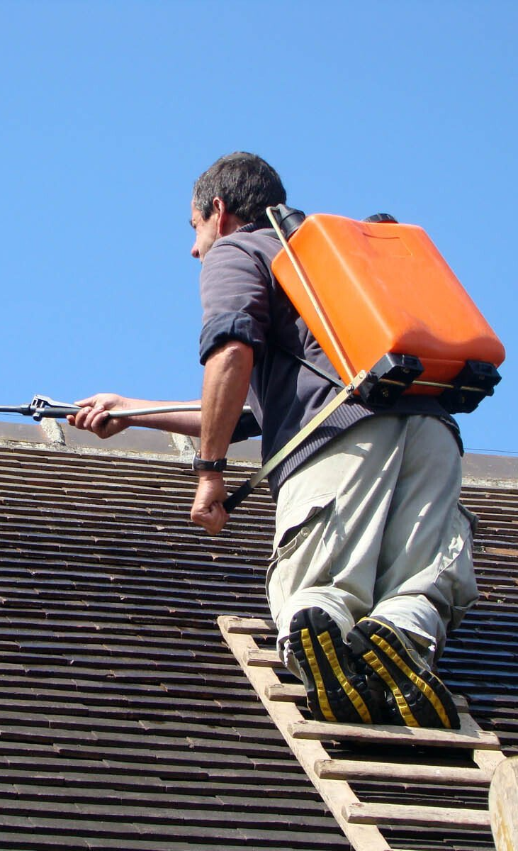 Couvreur en nettoyant une toiture avec un pulvérisateur