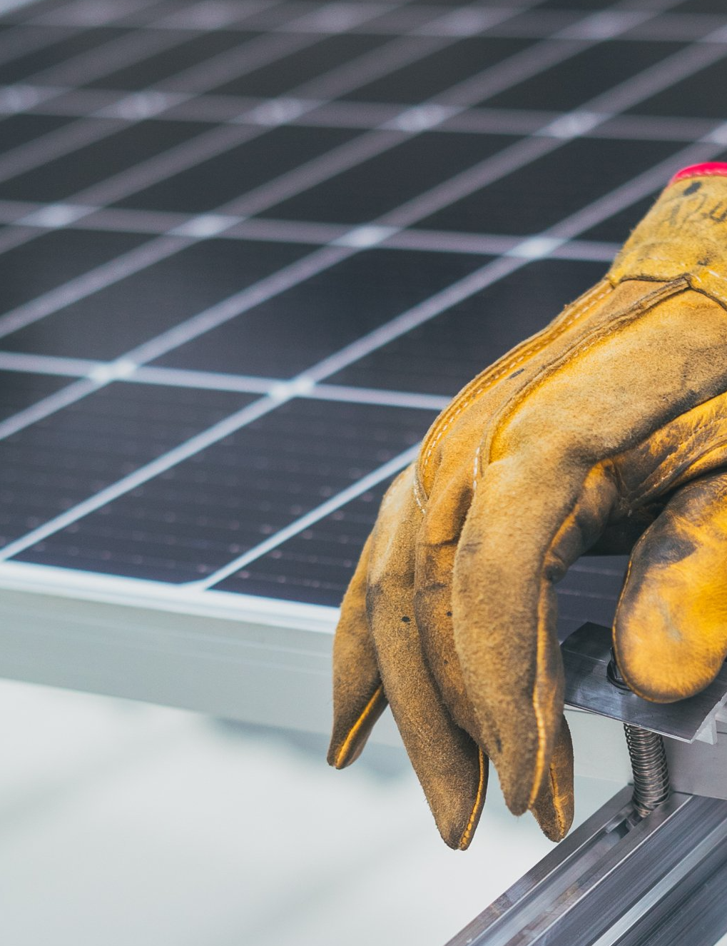 Main avec un gant jaune sur un panneau photovoltaïque