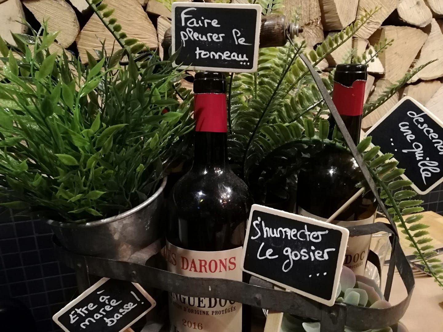 Bouteilles de vin avec des étiquettes à la craie dans un cadre rustique et verdoyant.