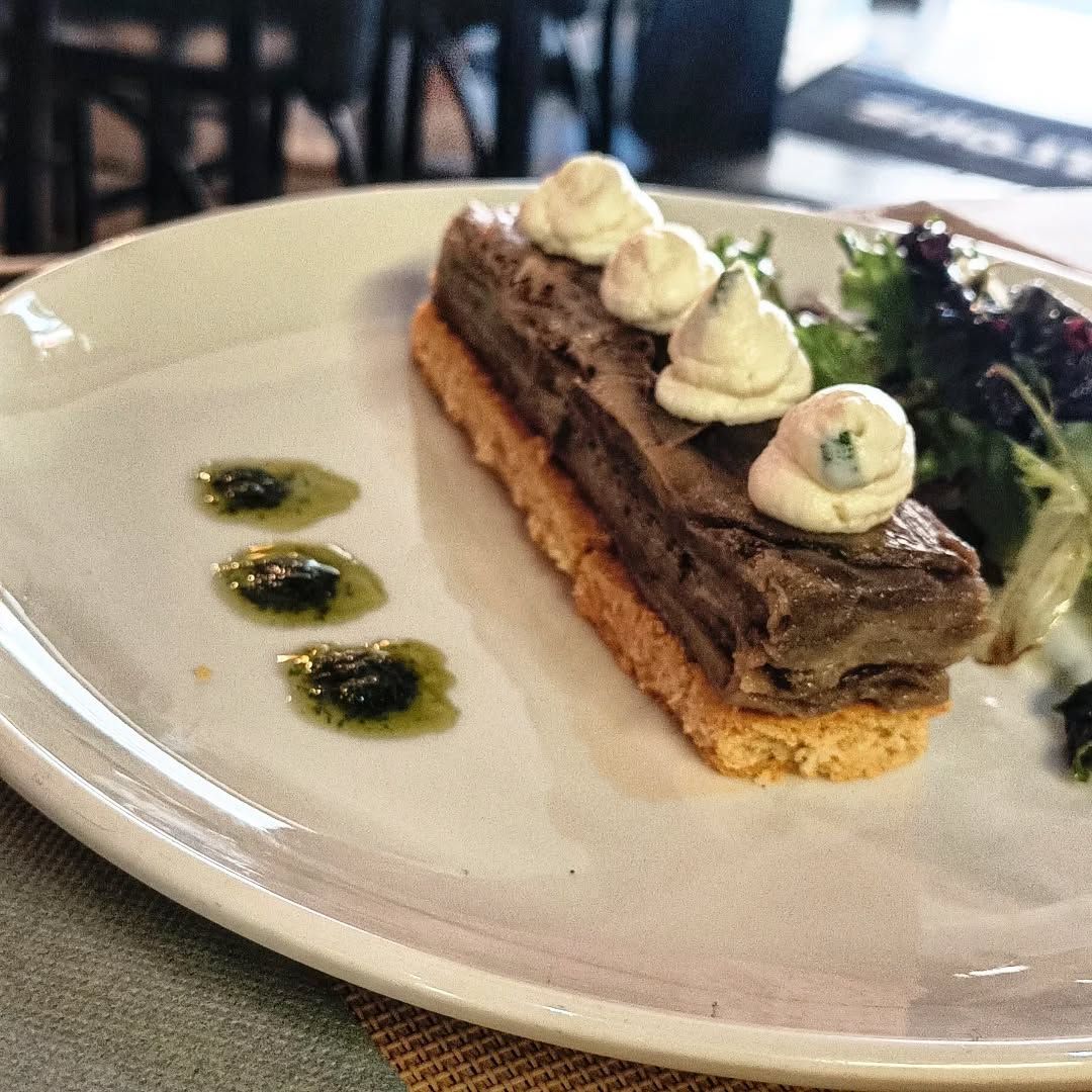 Plat de viande rectangulaire avec crème, sauce et légumes verts, servi sur une assiette blanche.