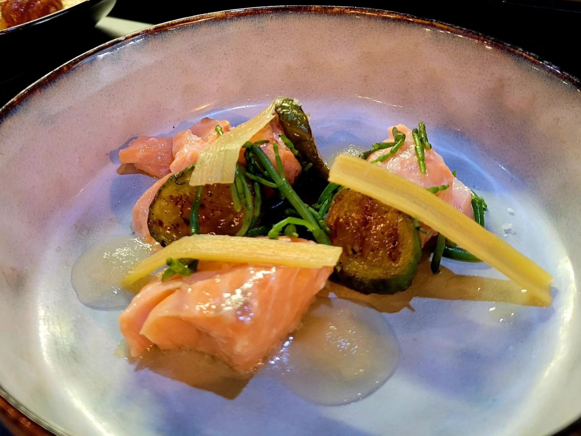 Saumon aux figues et à la verdure dans un bol clair ; teintes rose pâle, vertes et crème.