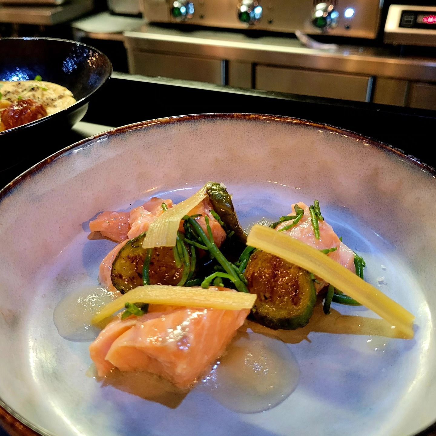 Une assiette composée de saumon, de courgettes et de sauce.