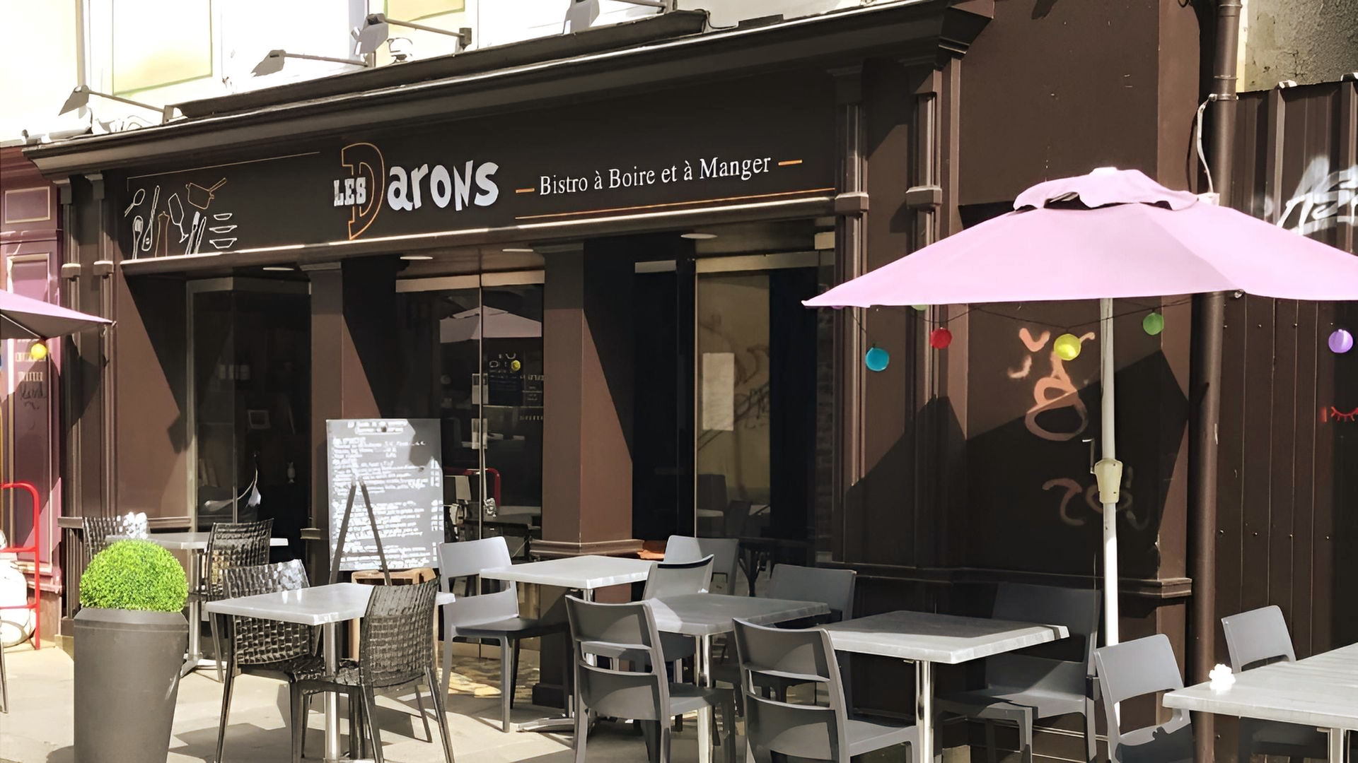 Extérieur du restaurant avec tables et parasols installés pour les repas en plein air.