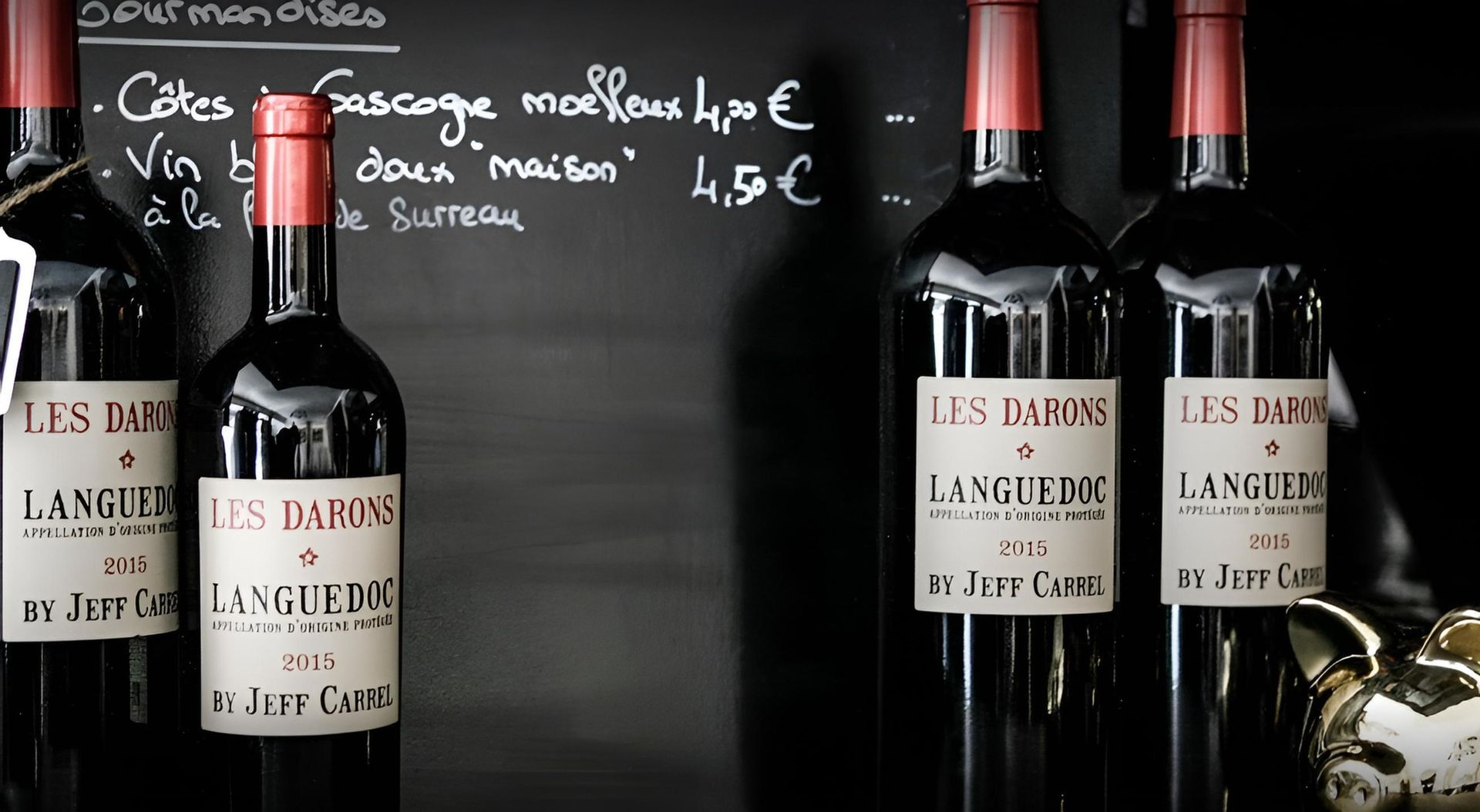 Bouteilles de vin sur fond sombre, avec des notes de menu manuscrites.