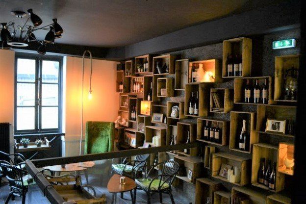 Intérieur d'un restaurant avec des caisses en bois contenant des bouteilles et une décoration sur un mur sombre.