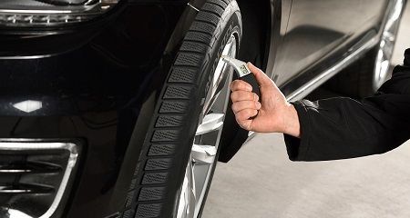 Una persona está ajustando un neumático de un automóvil con una llave inglesa.