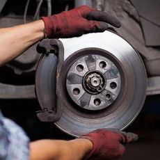 Una persona está arreglando un disco de freno en un coche.